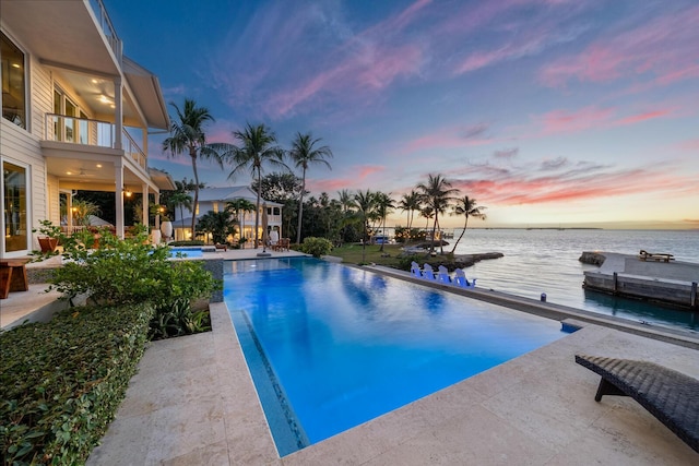 pool at dusk featuring a patio area and a water view