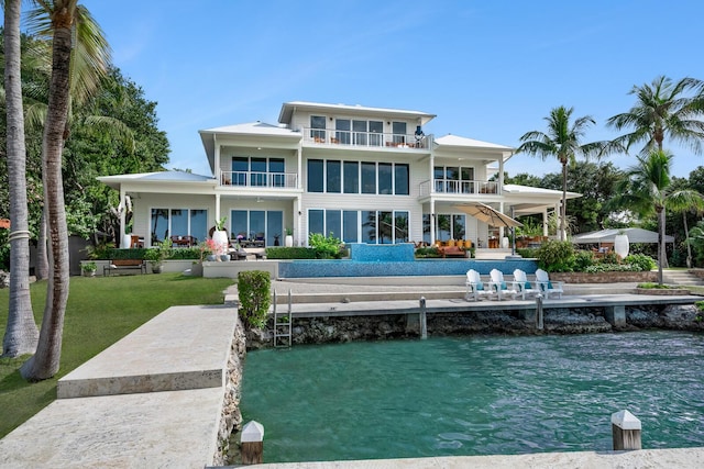 back of property with a yard, a patio area, a balcony, and a water view