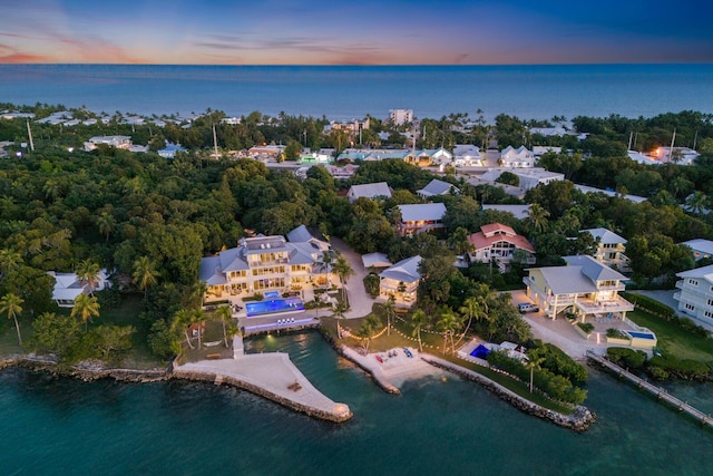 aerial view at dusk featuring a water view