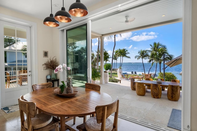 dining room with ceiling fan and a water view