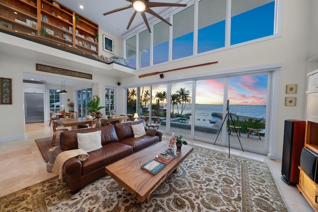 living room featuring a water view, ceiling fan, and a high ceiling