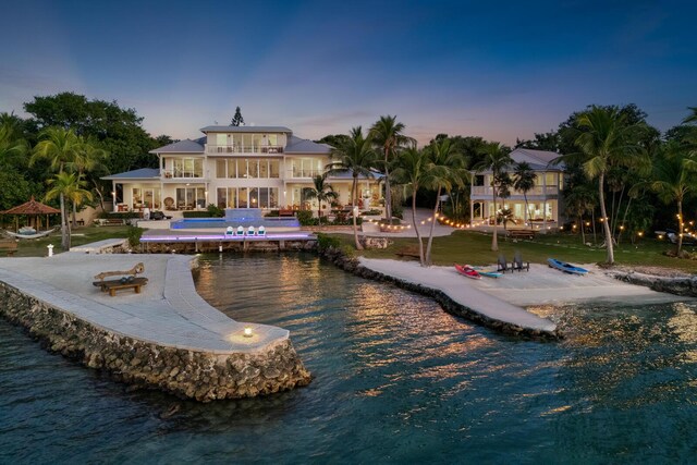 back house at dusk with a water view, a balcony, a gazebo, a swimming pool, and a patio