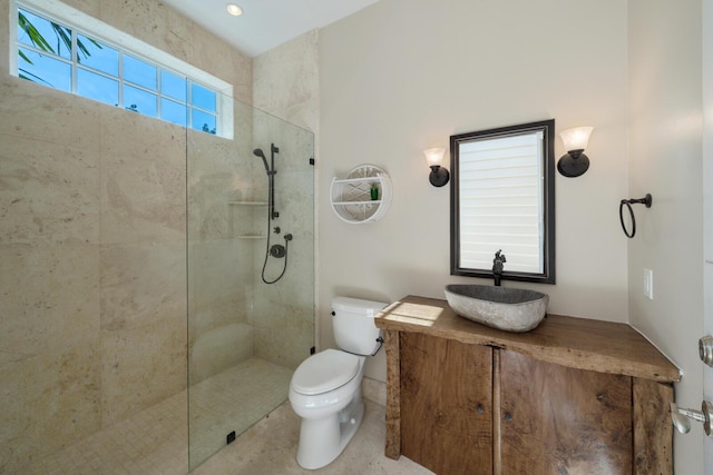 bathroom featuring a tile shower, vanity, and toilet