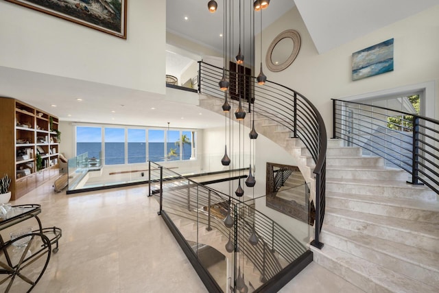 staircase featuring a high ceiling and a water view