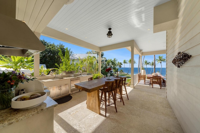 view of patio / terrace with a water view, exterior kitchen, and a wet bar