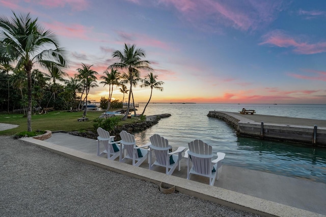 view of dock with a water view and a lawn