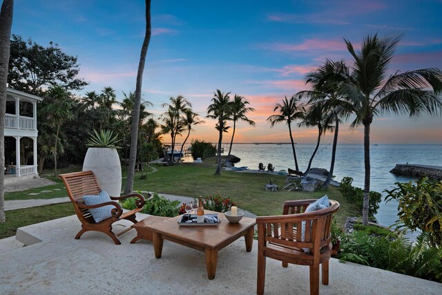 patio terrace at dusk with a water view and a yard