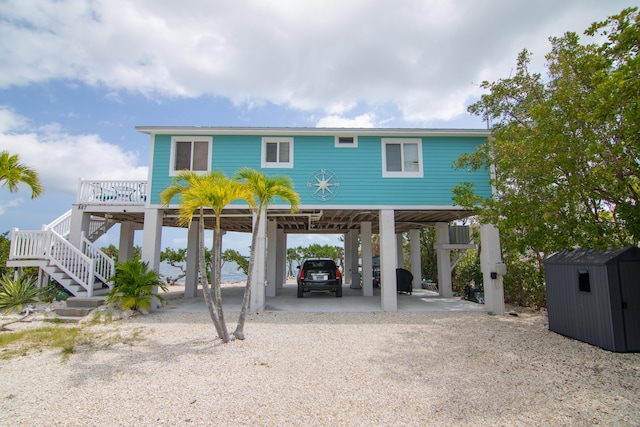 raised beach house featuring a carport and a shed