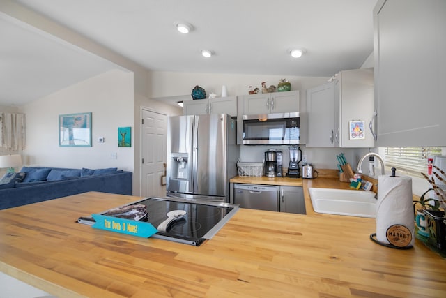 kitchen featuring lofted ceiling, sink, gray cabinetry, stainless steel appliances, and wood counters