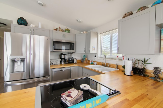 kitchen featuring sink, gray cabinets, stainless steel appliances, wood counters, and vaulted ceiling