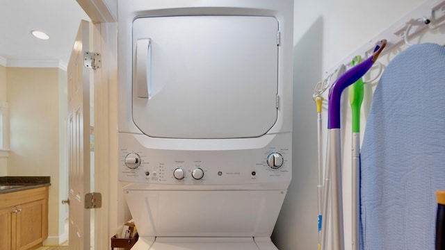 laundry room featuring ornamental molding and stacked washer / drying machine