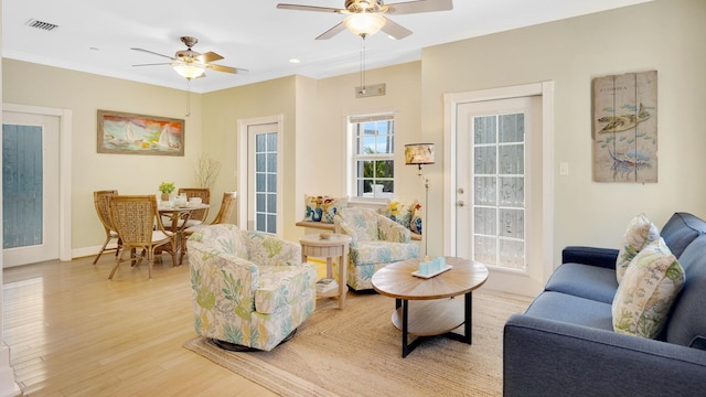 living room with crown molding, light hardwood / wood-style flooring, and ceiling fan