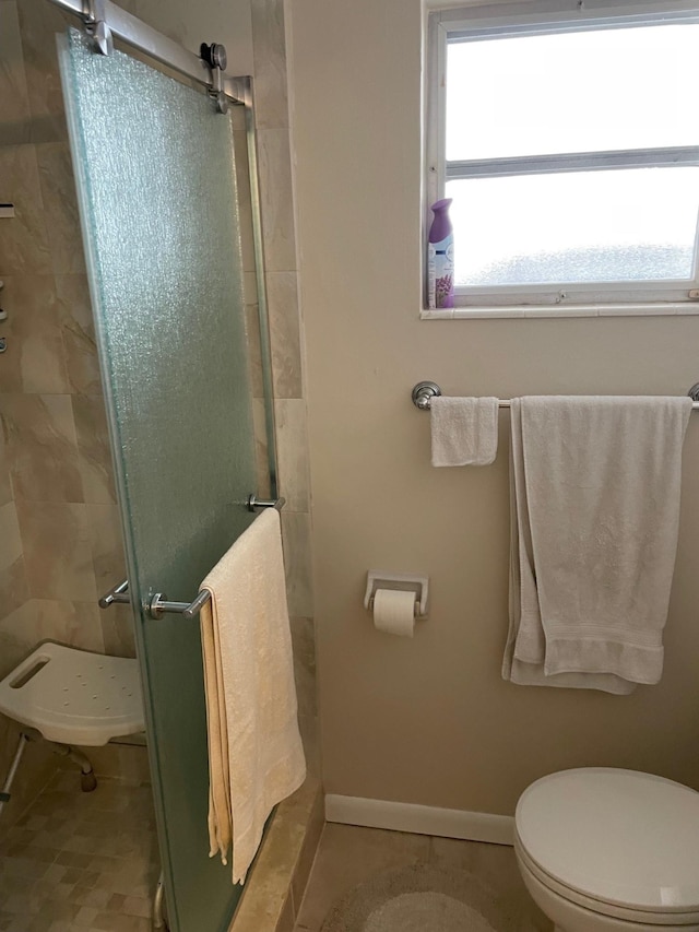 full bathroom featuring toilet, a stall shower, a wealth of natural light, and baseboards