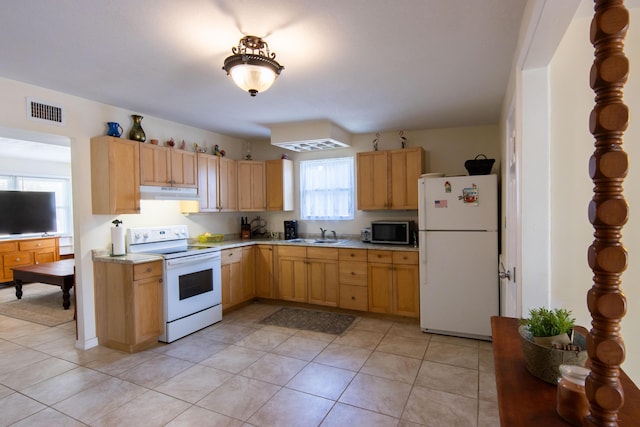 kitchen with light tile patterned flooring, light brown cabinetry, and white appliances