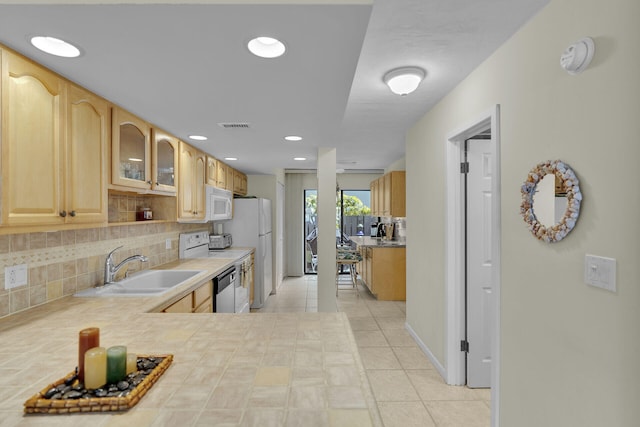 kitchen featuring light tile patterned flooring, light brown cabinetry, sink, white appliances, and decorative backsplash