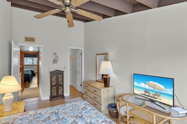 bedroom featuring beamed ceiling, a towering ceiling, and light hardwood / wood-style floors