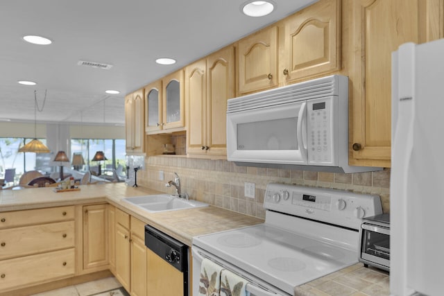 kitchen with white appliances, light brown cabinetry, and sink