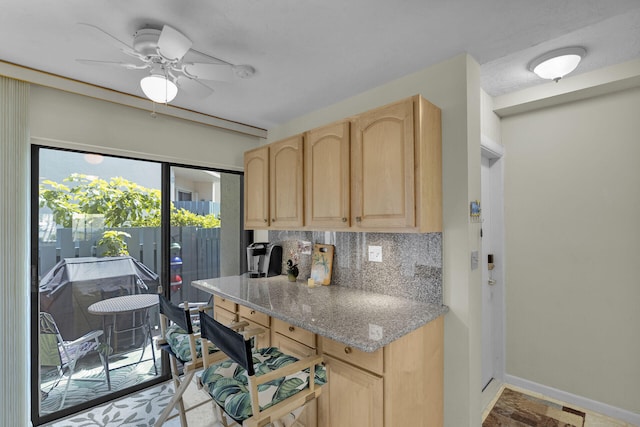 kitchen with light stone counters, ceiling fan, light brown cabinetry, and decorative backsplash