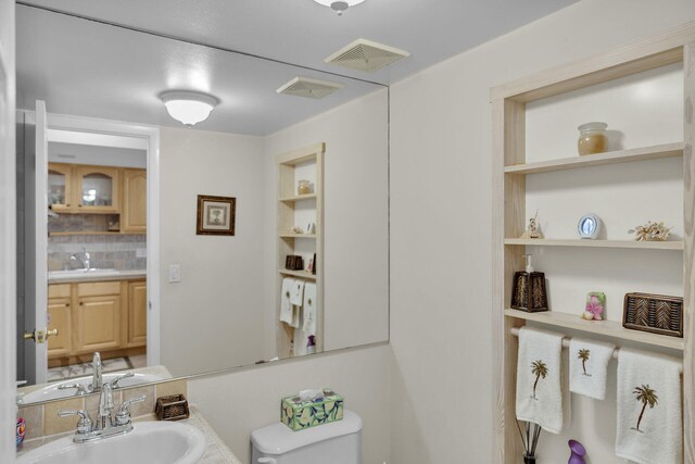 bathroom with vanity, backsplash, and toilet