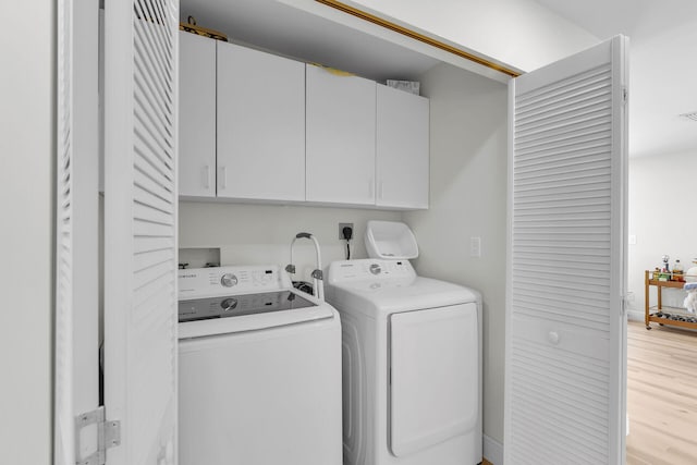 washroom featuring separate washer and dryer, cabinet space, visible vents, and light wood finished floors