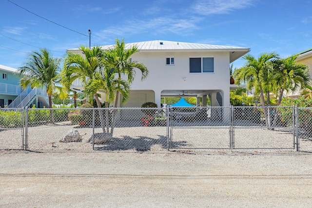 coastal inspired home featuring a carport, a gate, driveway, and stucco siding