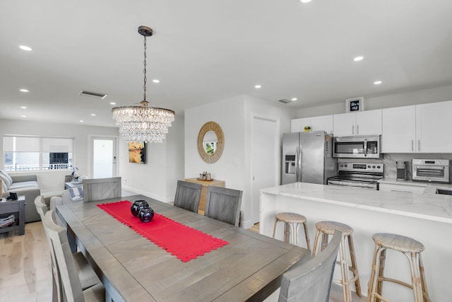 dining space featuring visible vents, recessed lighting, light wood-type flooring, and an inviting chandelier