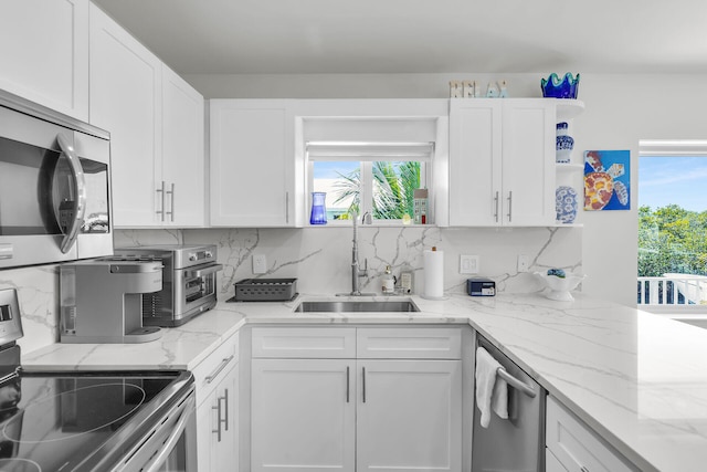 kitchen featuring white cabinets, tasteful backsplash, appliances with stainless steel finishes, and a sink