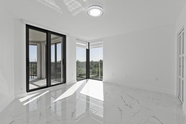 unfurnished room featuring expansive windows, baseboards, and marble finish floor