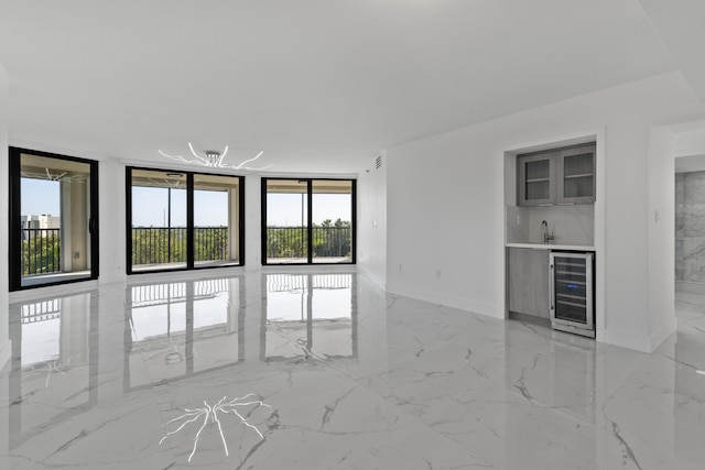 interior space featuring marble finish floor, beverage cooler, a sink, a wall of windows, and bar area