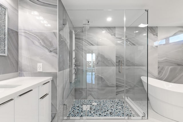 full bathroom featuring vanity, a soaking tub, a stall shower, tile walls, and marble finish floor