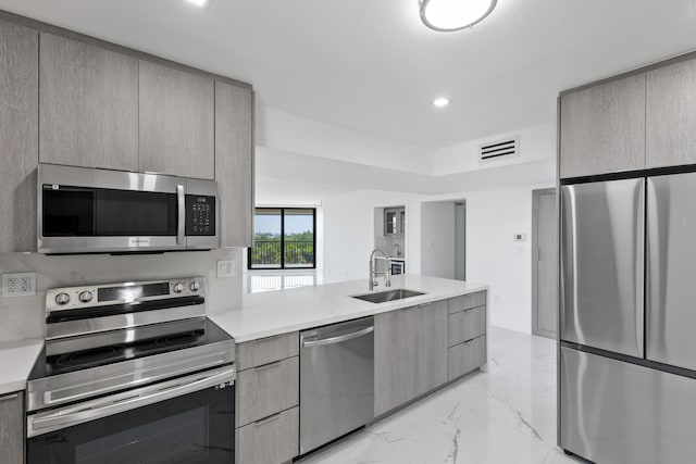 kitchen featuring visible vents, modern cabinets, a sink, stainless steel appliances, and light countertops