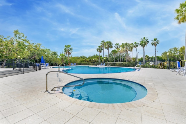 community pool with a patio area and fence