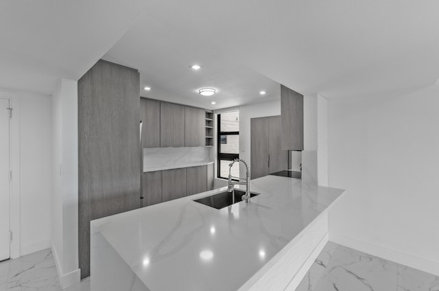 kitchen featuring marble finish floor, modern cabinets, a sink, recessed lighting, and baseboards