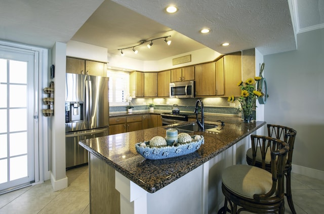 96000 Overseas Hwy Unit X54, Key Largo, FL 33037 - kitchen featuring stainless steel appliances, a sink, a peninsula, brown cabinetry, and light tile patterned floors