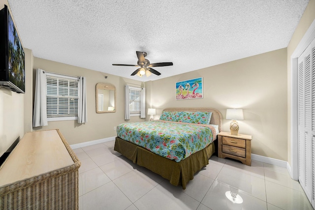 bedroom with a textured ceiling, light tile patterned flooring, and baseboards