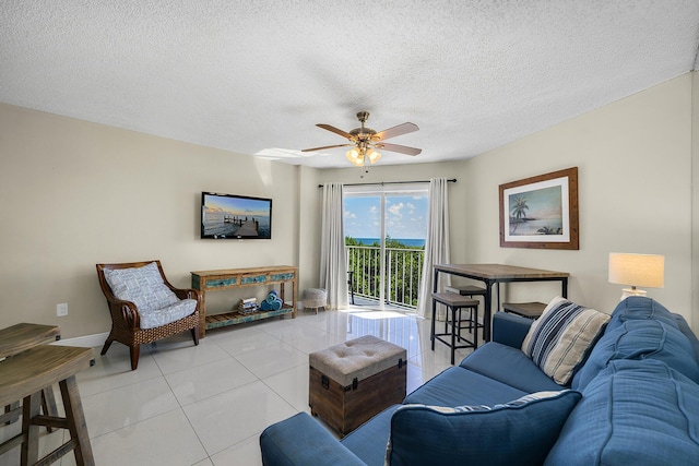 living area with light tile patterned flooring, ceiling fan, a textured ceiling, and baseboards