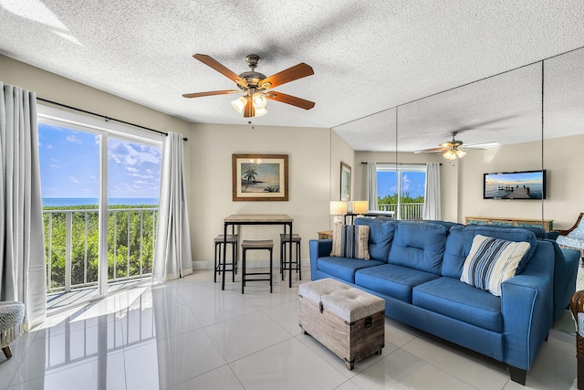 living area with ceiling fan, a textured ceiling, baseboards, and light tile patterned floors