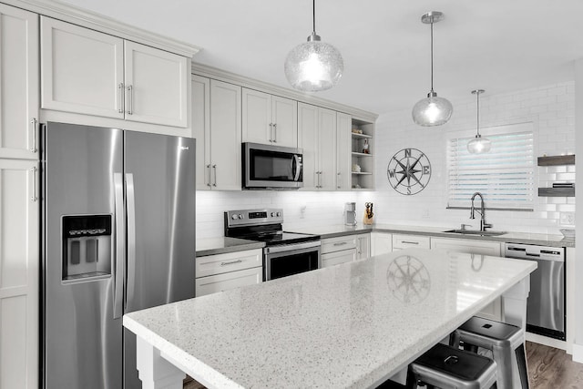 kitchen featuring appliances with stainless steel finishes, decorative light fixtures, sink, and white cabinets