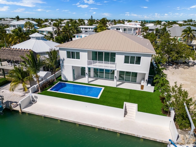 back of property with a balcony, a yard, a fenced in pool, a water view, and a patio area