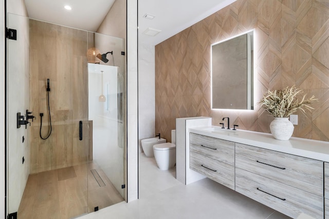 bathroom featuring a shower with shower door, tile walls, vanity, toilet, and a bidet