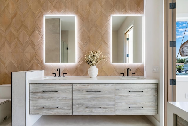 bathroom featuring tasteful backsplash, vanity, a healthy amount of sunlight, and toilet