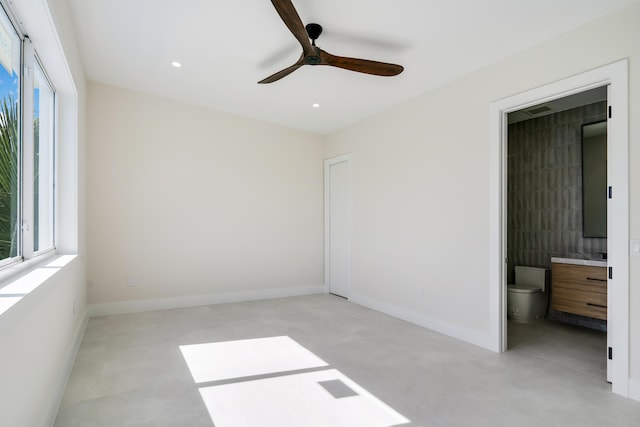 unfurnished bedroom with multiple windows, ceiling fan, and ensuite bath