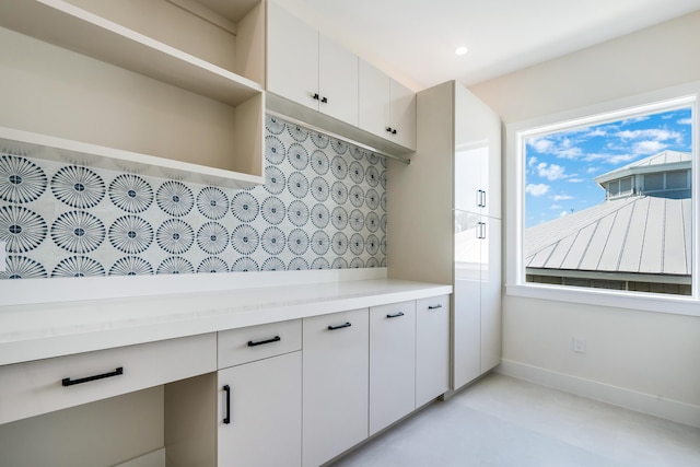 kitchen with light stone counters, backsplash, and white cabinets