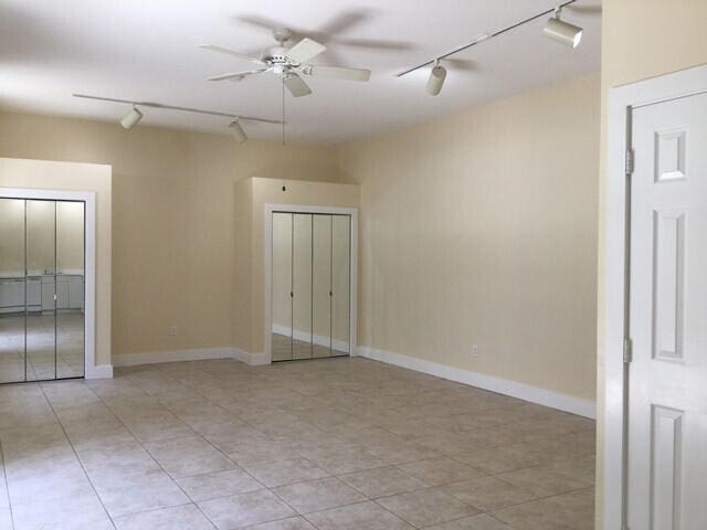 empty room with rail lighting and ceiling fan