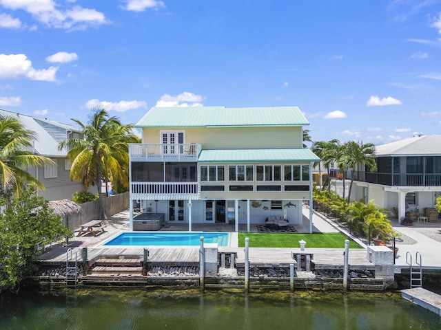 back of property featuring a hot tub, a water view, a balcony, french doors, and a patio