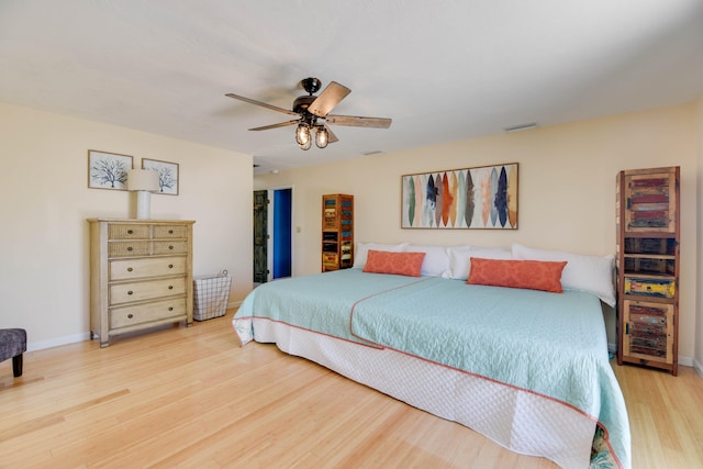 bedroom with visible vents, a ceiling fan, baseboards, and wood finished floors