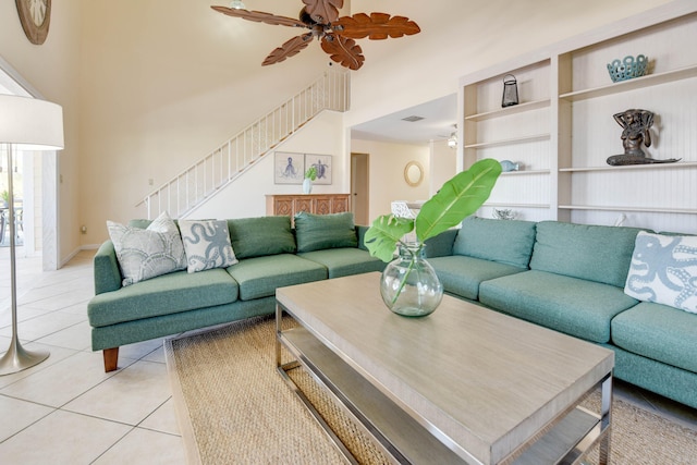 living area featuring a high ceiling, a ceiling fan, light tile patterned floors, visible vents, and stairway