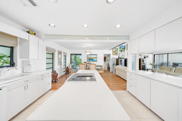 kitchen with electric stovetop, sink, and white cabinets