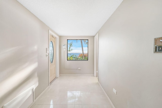 hallway with light tile patterned floors and a textured ceiling