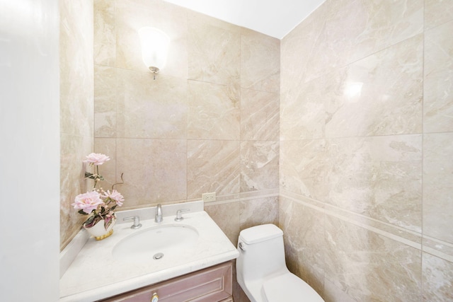 bathroom featuring vanity, tile walls, and toilet